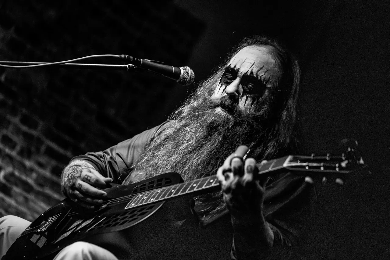 Reverend Meantooth in corpse paint playing a resonator guitar on stage